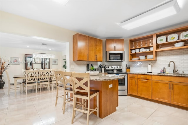 kitchen featuring brown cabinets, a sink, light stone counters, backsplash, and stainless steel appliances