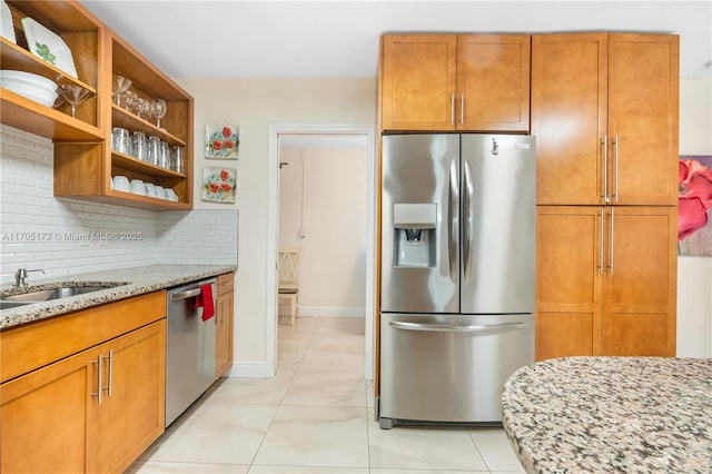 kitchen with light tile patterned floors, stainless steel appliances, backsplash, light stone countertops, and sink