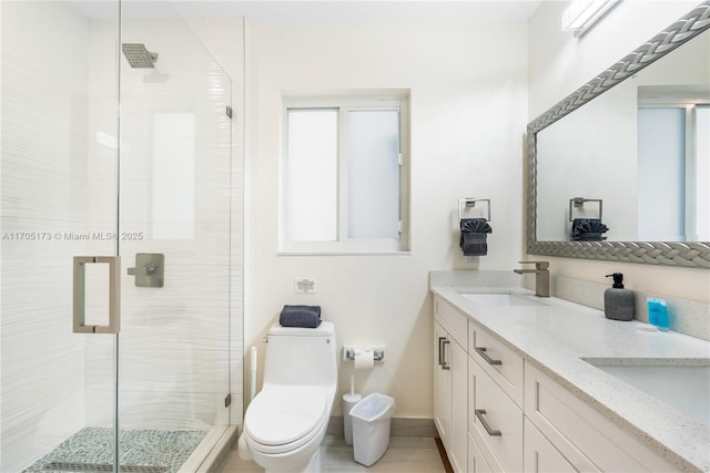 bathroom featuring toilet, a shower with shower door, and vanity