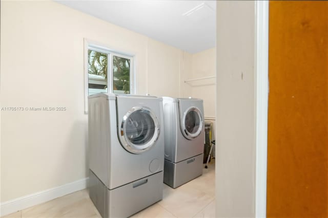 washroom with light tile patterned floors, laundry area, washing machine and dryer, and baseboards