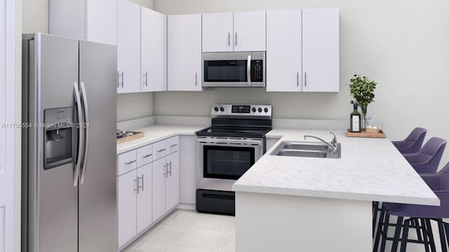 kitchen featuring kitchen peninsula, appliances with stainless steel finishes, white cabinets, and a kitchen breakfast bar