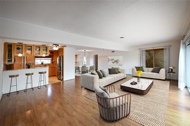 living room featuring ceiling fan, light hardwood / wood-style floors, and a textured ceiling