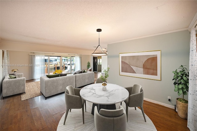 dining space featuring dark wood-type flooring, ornamental molding, and a textured ceiling