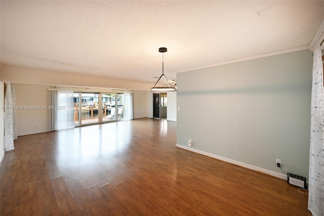 spare room with dark hardwood / wood-style flooring, ornamental molding, a textured ceiling, and baseboard heating