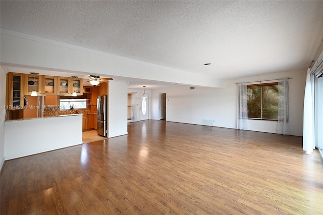 unfurnished living room with ceiling fan, a textured ceiling, and light hardwood / wood-style floors