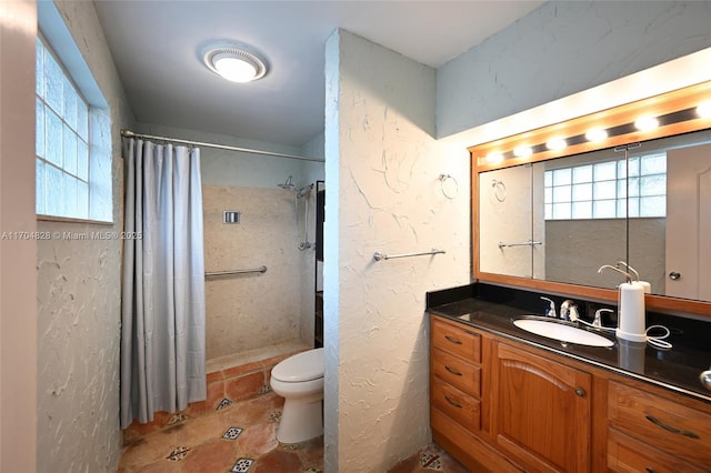 bathroom featuring vanity, toilet, a healthy amount of sunlight, and walk in shower