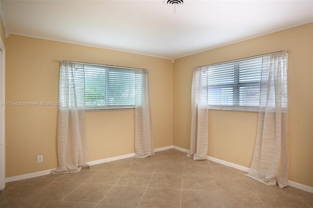 tiled spare room with ornamental molding and a wealth of natural light