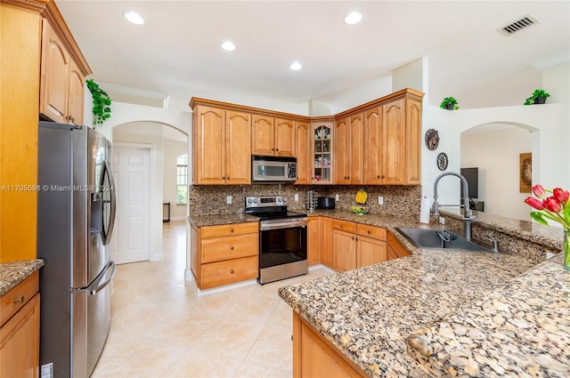 kitchen with stainless steel appliances, decorative backsplash, sink, stone countertops, and kitchen peninsula