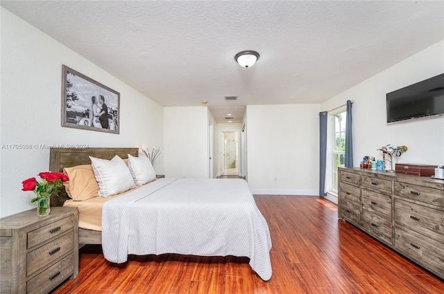 bedroom featuring a textured ceiling and dark hardwood / wood-style floors