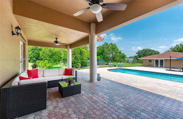 view of pool with ceiling fan, an outdoor living space, an outdoor structure, and a patio