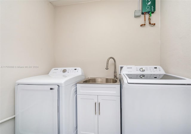 clothes washing area featuring sink, washing machine and clothes dryer, and cabinets