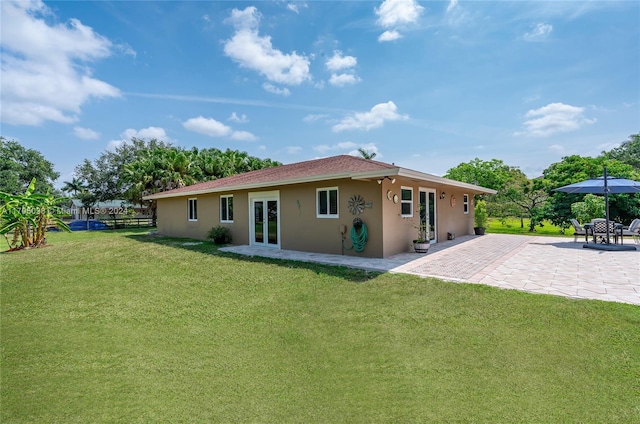 back of house featuring a lawn, a patio, and french doors