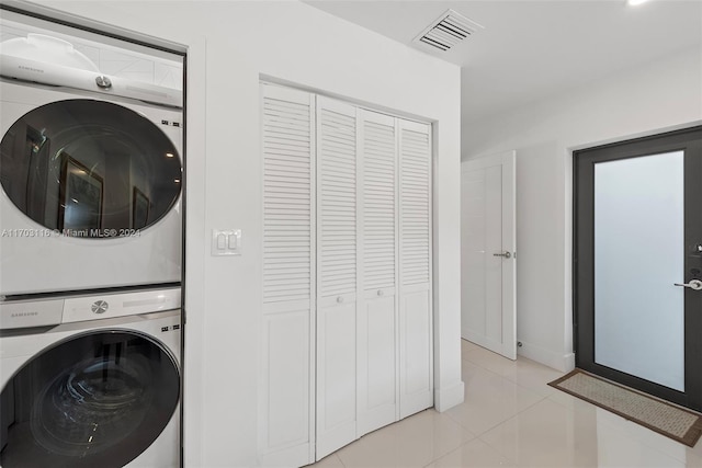 laundry room with stacked washer and clothes dryer and light tile patterned flooring