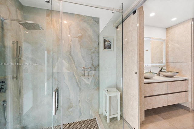 bathroom with vanity, tile patterned floors, tile walls, and a shower with shower door