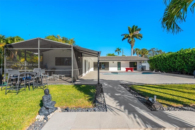 rear view of property with a lawn, glass enclosure, and a patio area