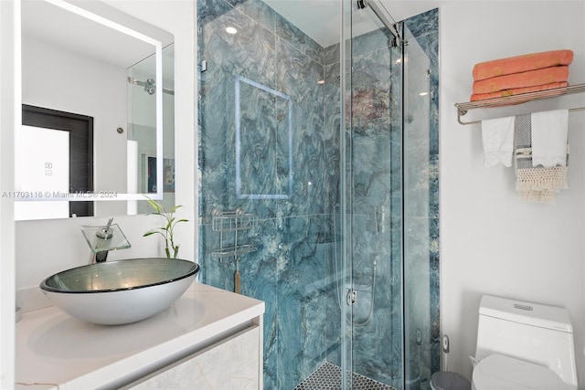 bathroom featuring a shower with door, vanity, and toilet