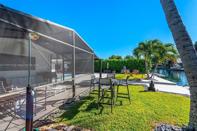 view of yard with a patio, a water view, and glass enclosure