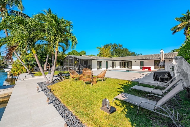 back of property with a lawn, glass enclosure, and a patio