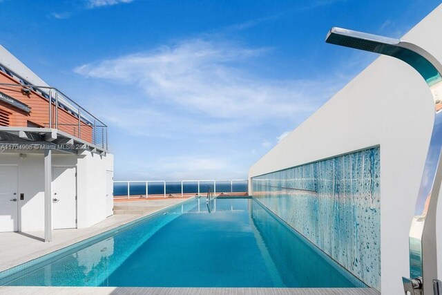 view of swimming pool with a water view and a patio