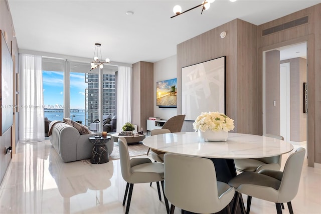 dining room with floor to ceiling windows, a water view, and a chandelier