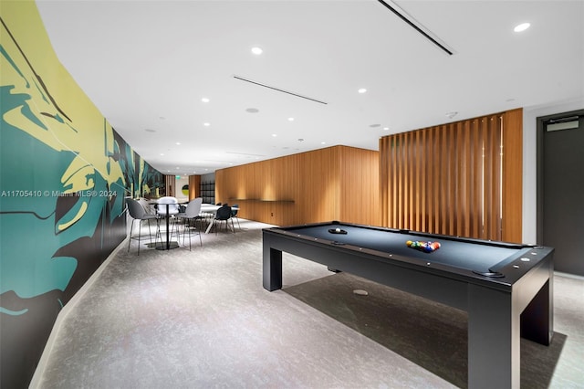 recreation room with wood walls and billiards