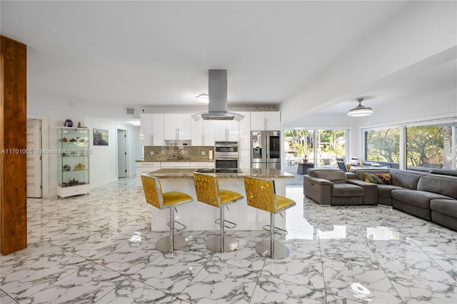 kitchen with stone counters, stainless steel appliances, white cabinets, island exhaust hood, and decorative backsplash