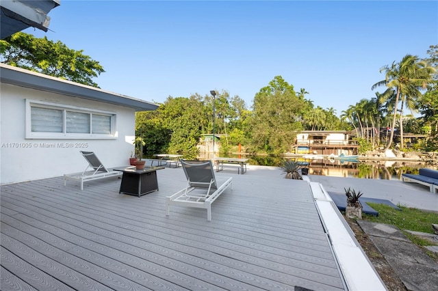 wooden terrace featuring a fire pit and a water view