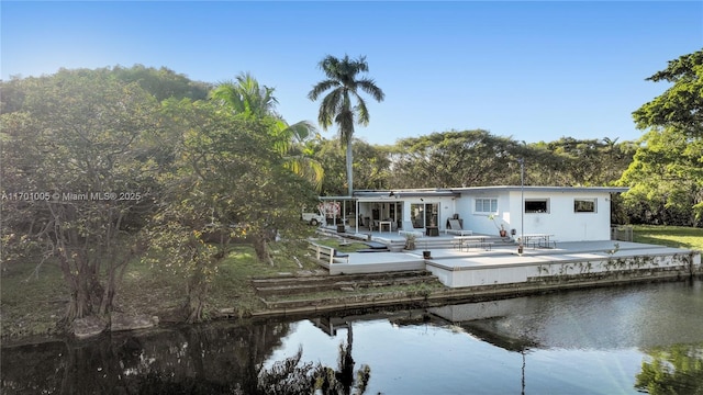 back of property with a patio and a deck with water view