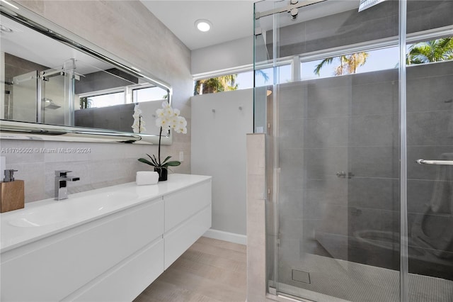 bathroom with a shower with door, vanity, and tile walls