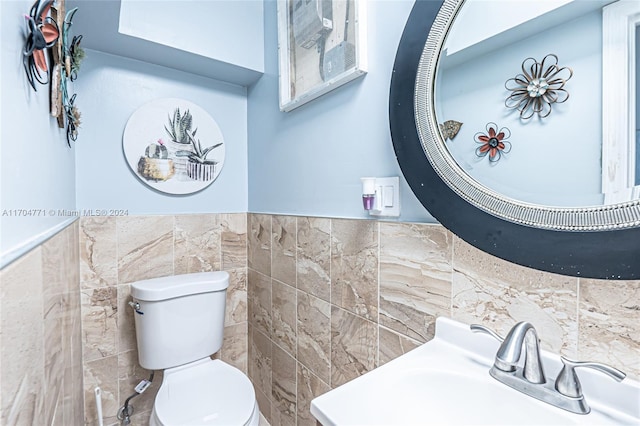 bathroom featuring sink, tile walls, and toilet