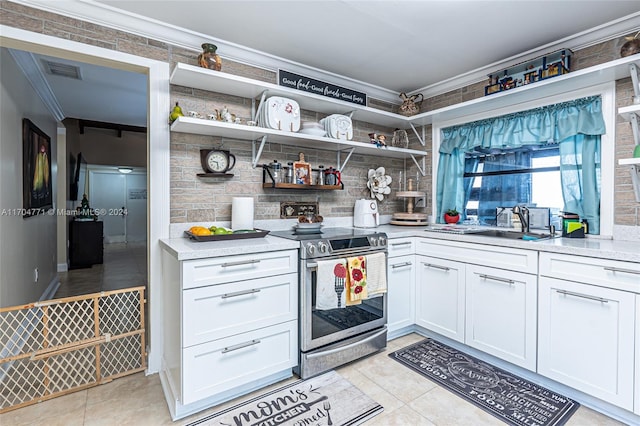 kitchen with white cabinets, light tile patterned floors, stainless steel electric stove, and crown molding