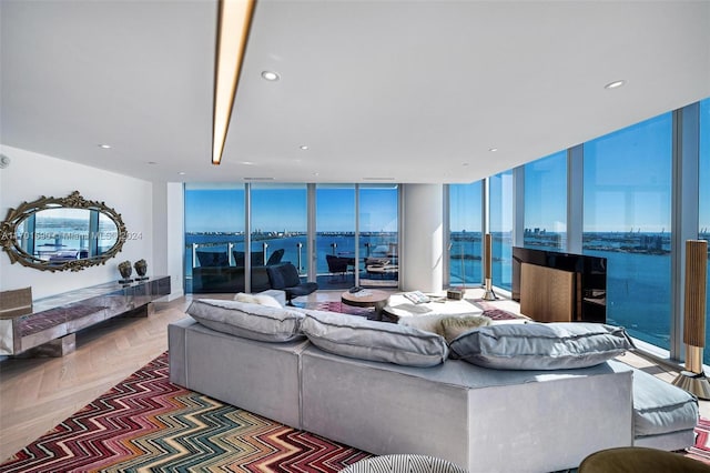 living room featuring parquet floors, a wealth of natural light, a water view, and a wall of windows