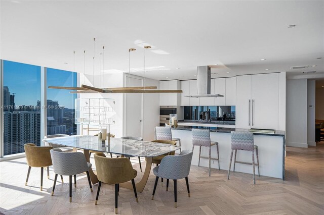 kitchen featuring white cabinets, a breakfast bar, range hood, and light parquet floors