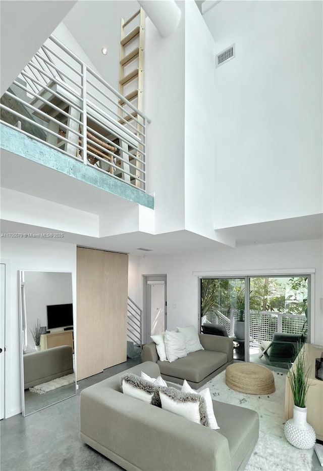 living room featuring stairs, visible vents, a towering ceiling, and finished concrete floors