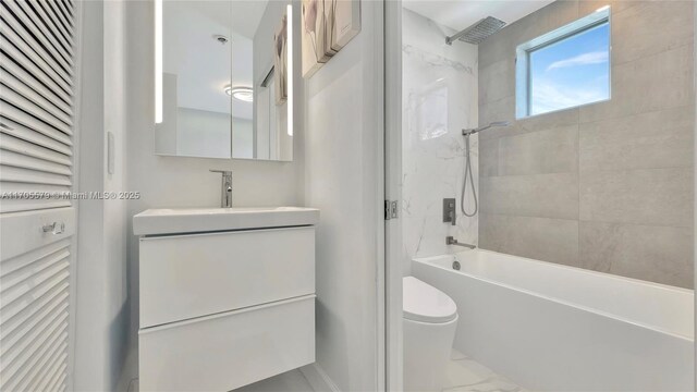 full bathroom featuring tiled shower / bath, vanity, and toilet