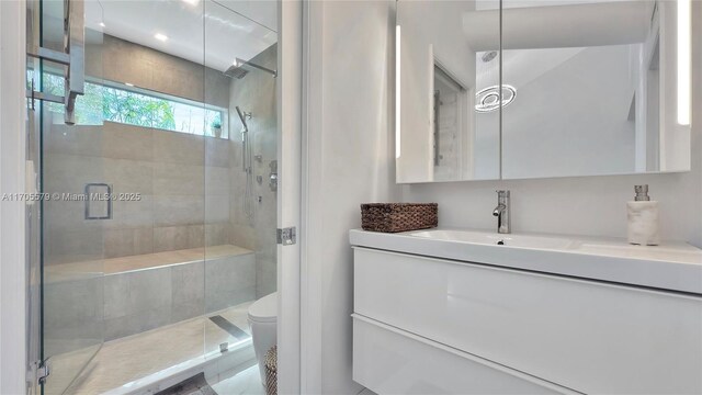 bathroom featuring tile patterned floors, vanity, toilet, and a shower with shower door