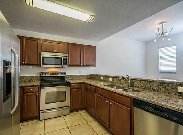 kitchen featuring stainless steel appliances, sink, light tile patterned floors, stone countertops, and a chandelier