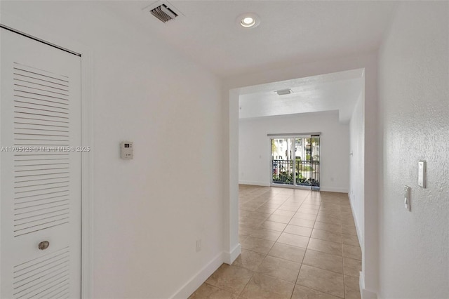 corridor with visible vents, baseboards, and light tile patterned floors