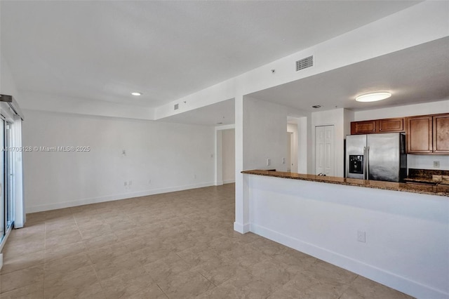 kitchen featuring visible vents, baseboards, dark stone counters, and stainless steel fridge with ice dispenser