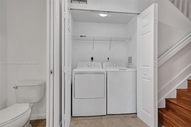 washroom featuring laundry area, light tile patterned floors, visible vents, baseboards, and washing machine and dryer