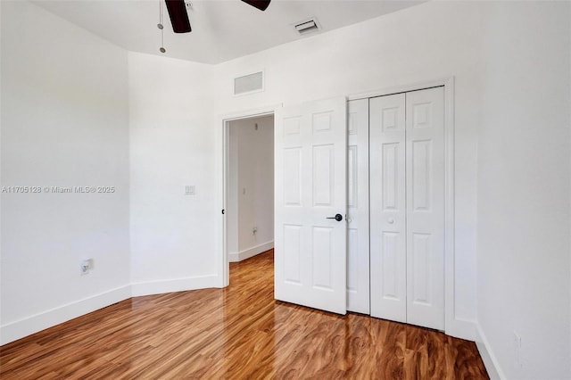 unfurnished bedroom featuring a closet, visible vents, baseboards, and wood finished floors