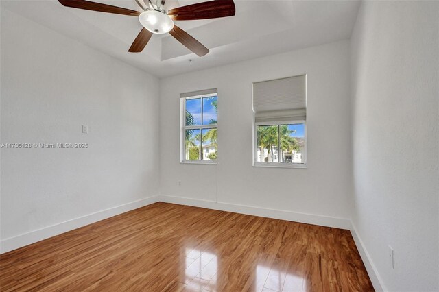 unfurnished room with ceiling fan, wood finished floors, and baseboards