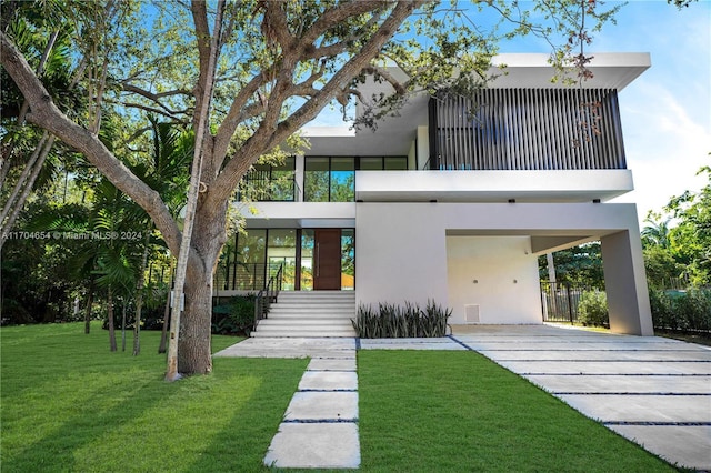 back of property with a lawn, a carport, and a balcony