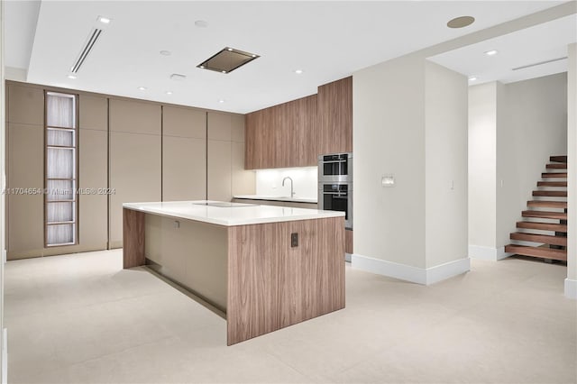 kitchen featuring stainless steel double oven, black electric cooktop, a kitchen island, and sink