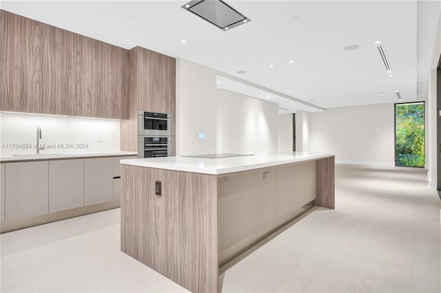 kitchen with a large island, black electric cooktop, sink, and double oven