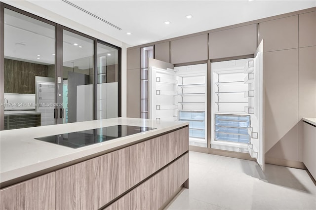 kitchen with black electric stovetop and light brown cabinetry