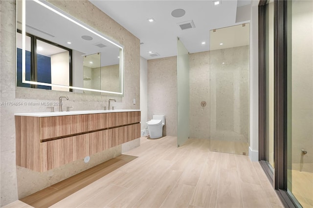 bathroom with a shower, wood-type flooring, vanity, and toilet