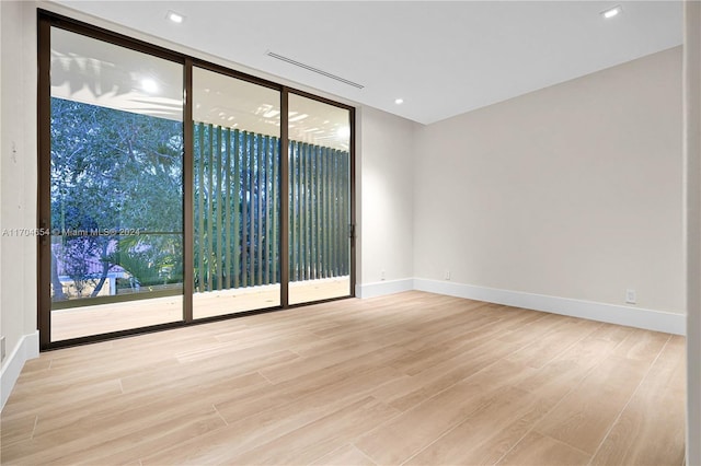 spare room with light hardwood / wood-style floors and a wall of windows