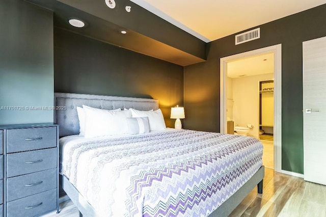 bedroom featuring light wood-type flooring and ensuite bath