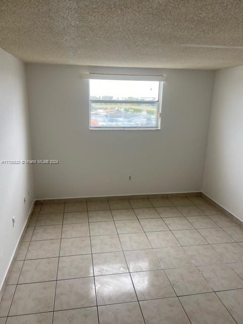 tiled empty room featuring a textured ceiling